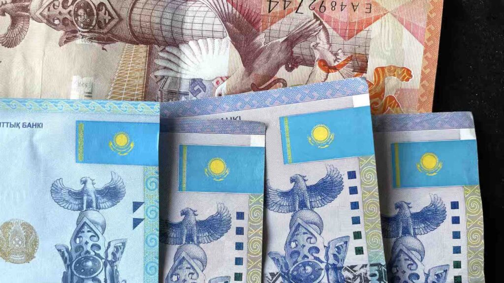 Купюры в 5000, 500 и 10000 тенге на темном фоне