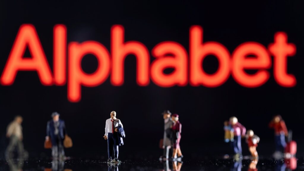 Логотип Alphabet, перед которым стоят игрушечные люди