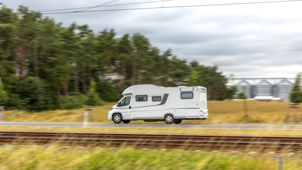 A white camper van driving on the road, motion blur effect highlights the sense of speed and freedom of travel.