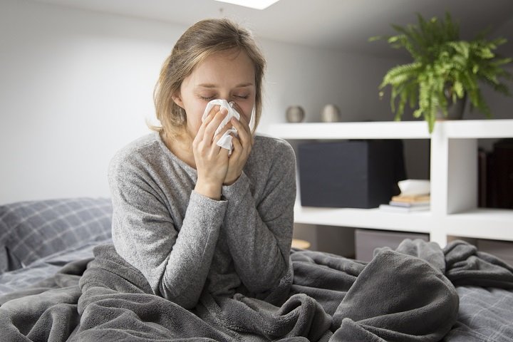 sick woman sitting bed blowing nose with napkin - Bizmedia.kz