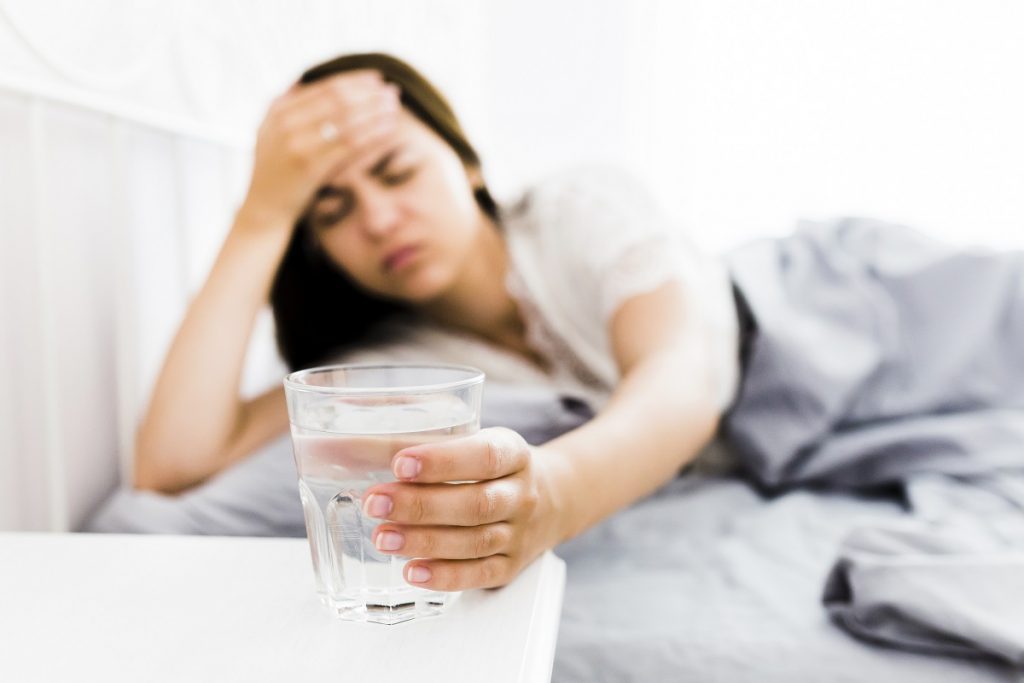 woman with headache taking glass water - Bizmedia.kz