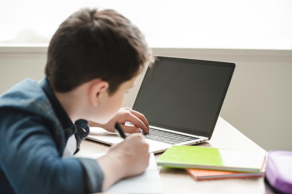 stock photo schoolboy writing notebook using laptop - Bizmedia.kz