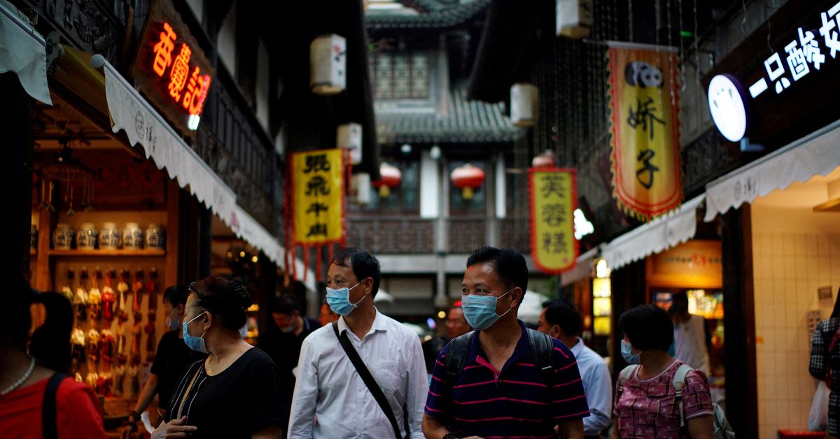People wearing face masks walk on Jinli Ancient Street in Chengdu