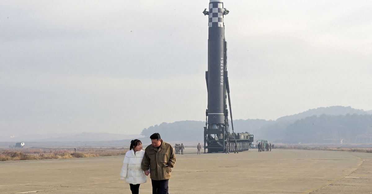 North Korean leader Kim Jong Un, along with his daughter, walks away from an ICBM in this undated photo released by KCNA