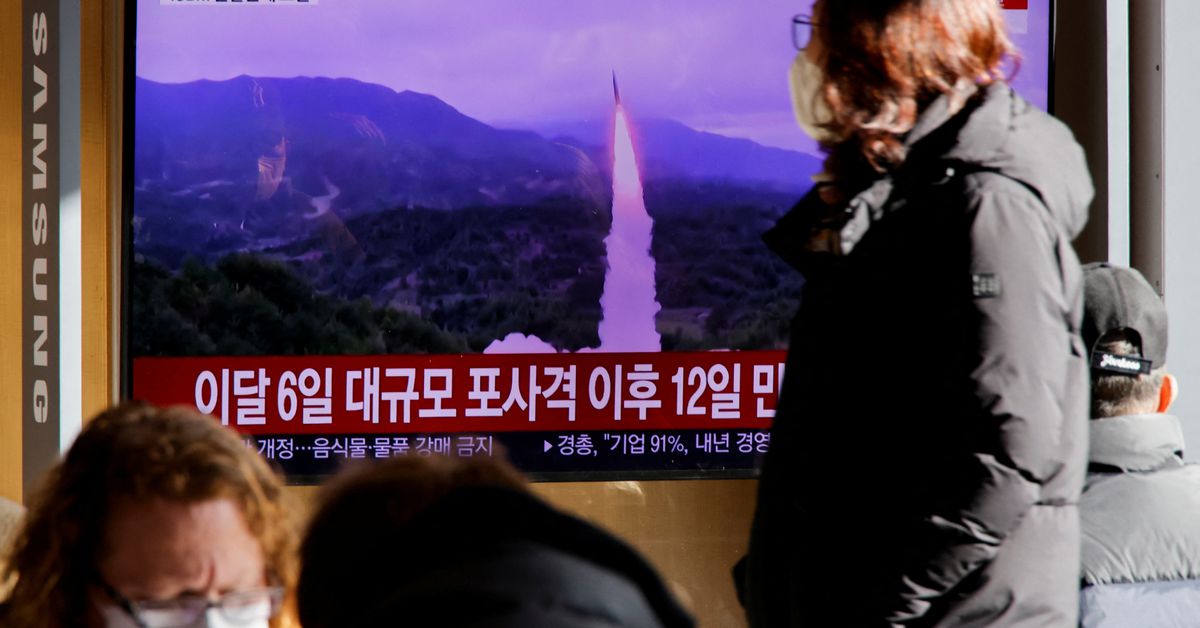 A woman walks past a TV broadcasting a news report on North Korea firing a ballistic missile off its east coast, in Seoul